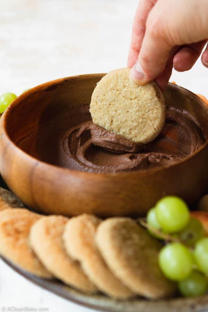 Cookie scooping chocolate dessert hummus out of a bowl