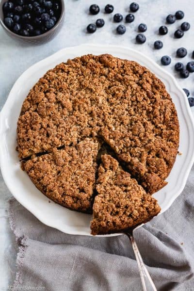 Paleo blueberry crumb cake on a plate with a spatula pulling a slice out