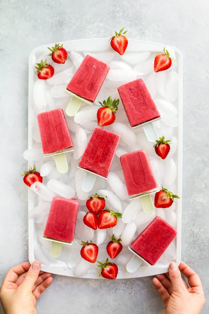 Tray of Strawberries and Cream Popsicles (gluten free, paleo, vegan, and naturally sweetened) with ice and fresh strawberries