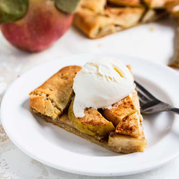 Slice of paleo gluten free apple galette on a plate topped with ice cream and with a fork