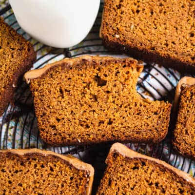 Slices of paleo gluten free pumpkin bread on a cooling rack with a glass of milk