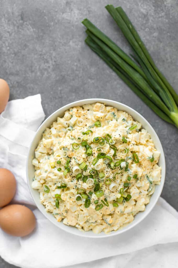 Egg salad on a table with eggs and scallions
