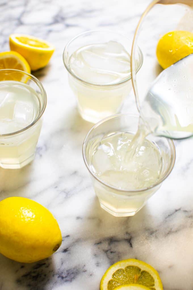 Glass of Sugar Free Lemonade surrounded by lemons on a marble table