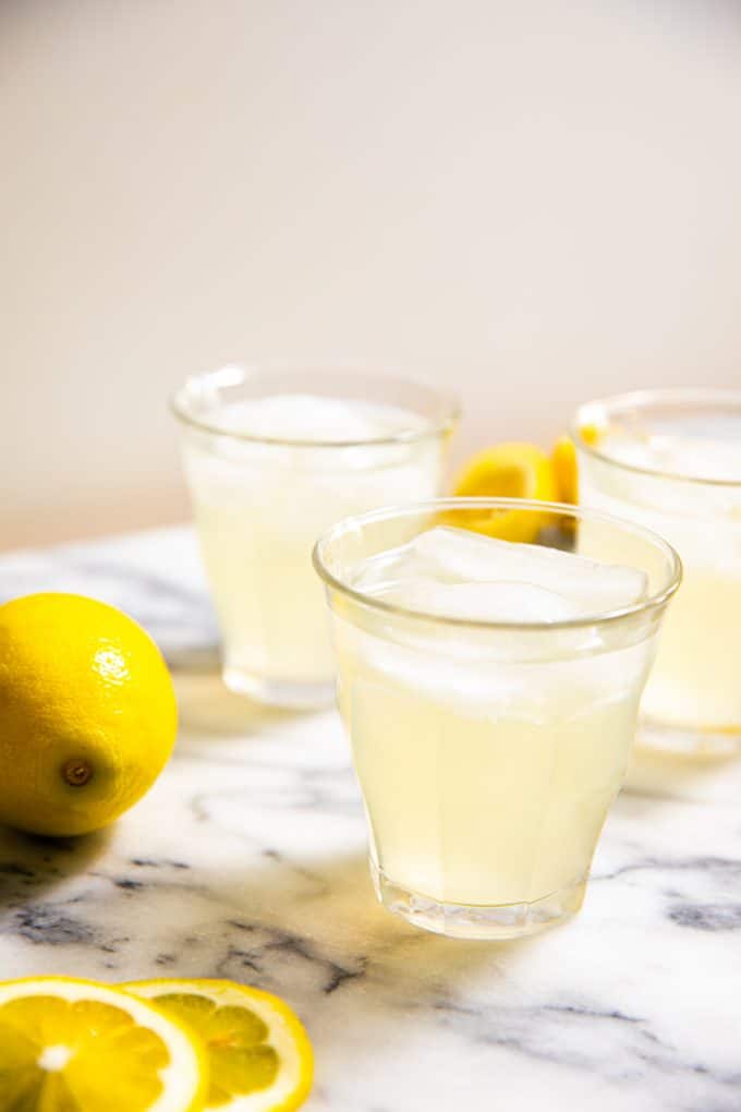 Glass of Sugar Free Lemonade surrounded by lemons on a marble board