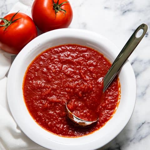 Bowl of pizza sauce with a ladle in it