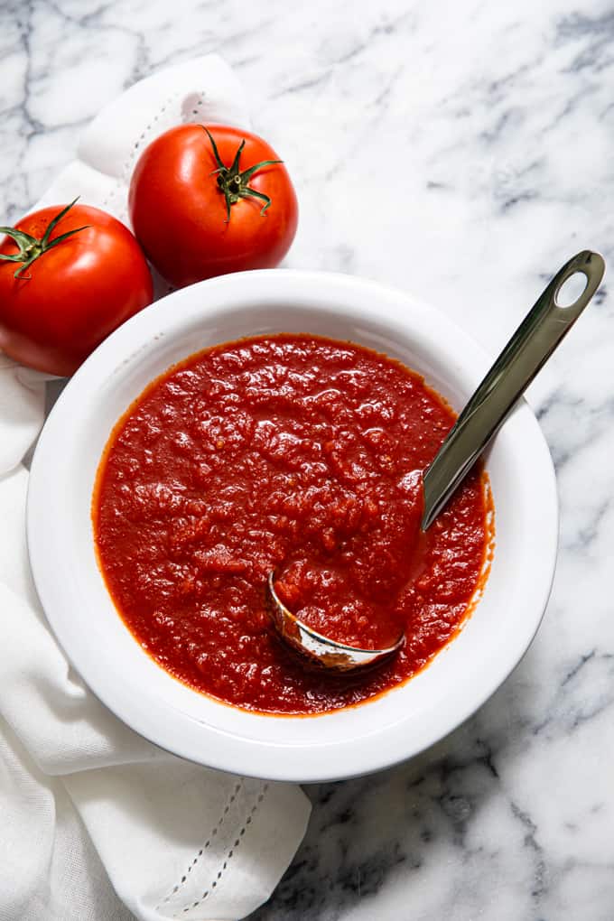 Bowl of pizza sauce with a ladle in it