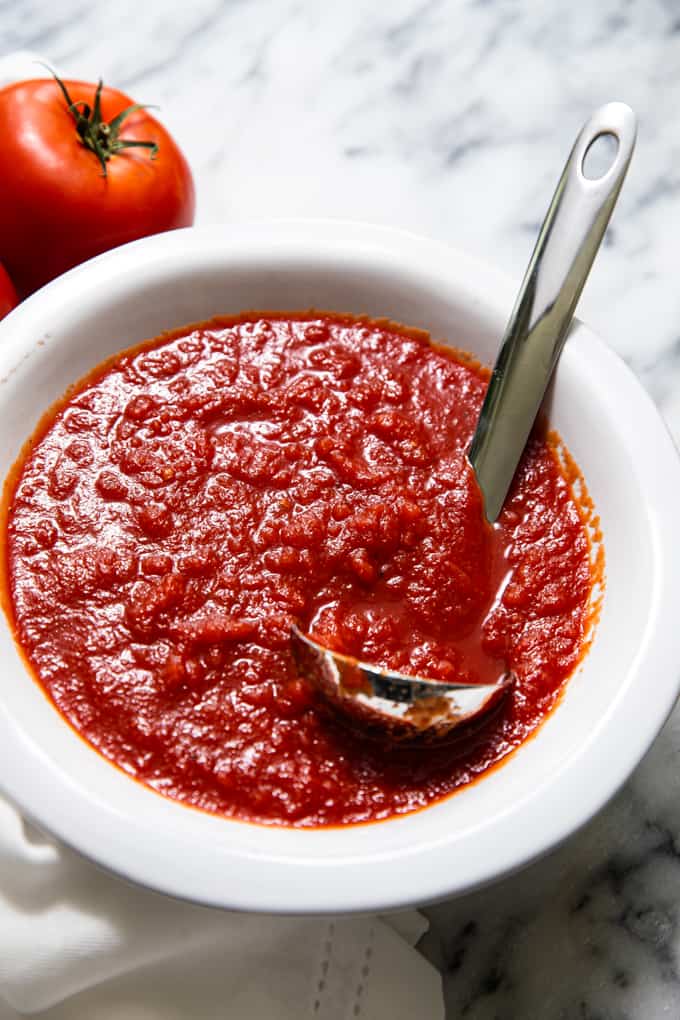 Bowl of simple pizza sauce with a ladle resting in it