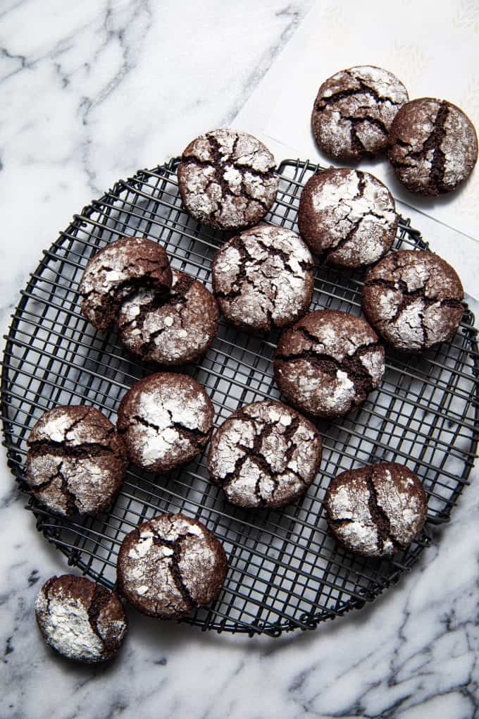 Array of Paleo gluten free chocolate crinkle cookies spilling off of a round wire rack